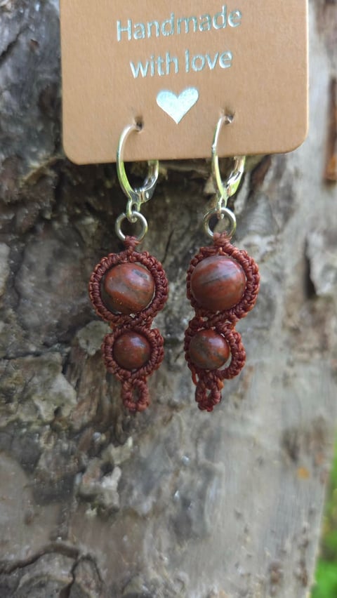 Pair of handmade earrings with rust-colored macramé woven around brown beads, displayed on a kraft paper tag with Handmade with love text and a white heart