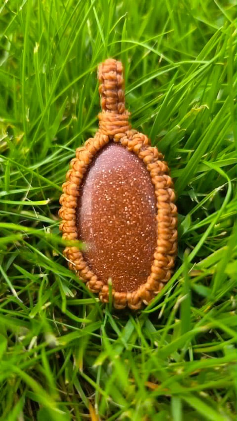 Engorged tick with reddish-brown body surrounded by bumpy orange mouthparts on green grass